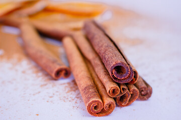 A pile of orange slices and cinnamon sticks on a white background. The oranges are cut in half and the cinnamon sticks are whole. Concept of warmth and comfort
