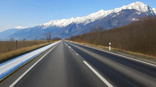 A road with a snowy mountain in the background. The road is empty and the sky is clear