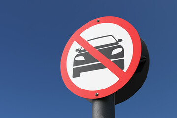 Round road sign showing a black vehicle behind a red forbidden symbol under blue sky. Illustration of the concept of car free zone and ultra low emission zone (ULEZ)