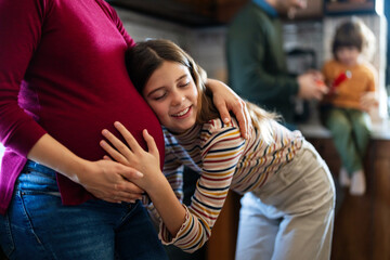 Obraz premium Lovely daughter touching mother's pregnant belly. Happy little girl feeling baby at mother tummy