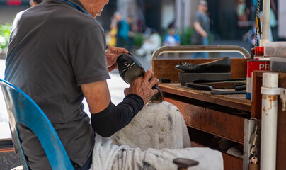 Shoemaker Repairing Shoes In The Street In Singapore