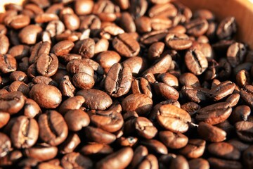 Un tas de grains de café à la lumière du soleil,  avec effet de lumière chaude et ombres marquées	