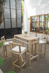 A modern and stylish set of wooden bar stools and a table, perfect for outdoor dining or a relaxed cafe setting.
