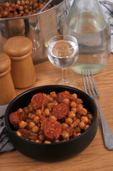 Ramequin de pois chiches et rondelles de chorizo avec une fourchette et un verre d'eau en gros plan
