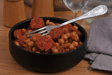 Ramequin de pois chiches et rondelles de chorizo avec une fourchette en gros plan