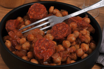 Ramequin de pois chiches et rondelles de chorizo avec une fourchette en gros plan