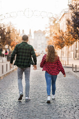 A Fashionable Young Couple Strolling Hand in Hand Through a Charming City Street During Autumn