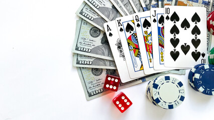 Poker chips, playing cards showing a royal flush in spades, red dice, and US dollar bills placed on a white background, representing gambling, luxury, and high-stakes poker. Ideal for casino advertise