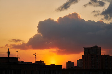 Fototapeta premium Crane and Buildings Silhouetted Against a Vibrant Sunset