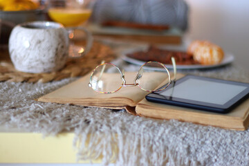 Books, e-reader, tea, orange juice, fruit, snacks, yarn, blanket and lit candles on the table....