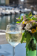 glass of white wine with flowers with a marina iin the background