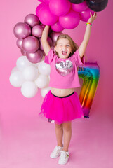 Happy Birthday. Happy girl laughs holding inflated balloons in her hands. Behind on a pink background is a multi-colored number seven..Emotions of happiness.