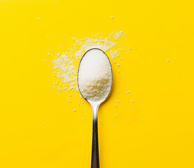 Spoon photo of white sugar powder on the spoon on a yellow background