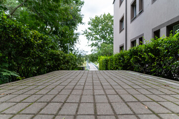 Pathway through lush greenery leading to a residential building on an overcast day