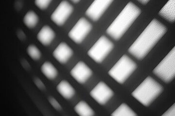 Black and white abstract shadow patterns from a grid on a surface create a dramatic contrast, playing with light and form for an artistic effect.