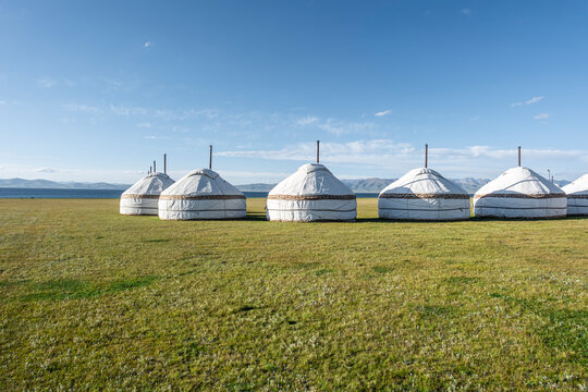Traditional yurts dotting the picturesque landscapes near Song-Kol Lake in bright daylight, Kyrgyzstan, Central Asia