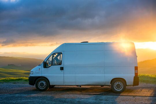 Camper van parked on the side of the road on a green Tuscan landscape at sunset, Tuscany, Italy