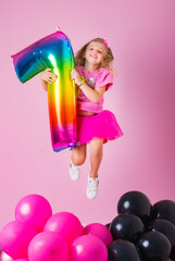 Happy Birthday. Happy girl jumping, holding colorful number 7 in her hands on a pink background. Emotions of happiness.