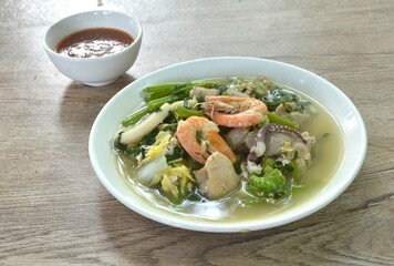 boiled sukiyaki seafood chicken and pork meat couple crispy pickled squid and shrimp with vegetable in soup on plate dipping sauce