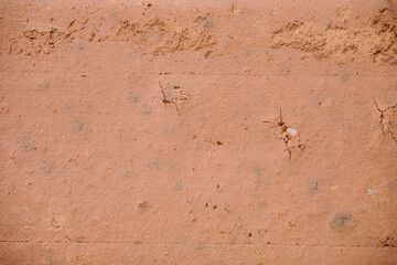 Close-up view of a textured surface, likely a brick or stucco, exhibiting a light reddish-brown...