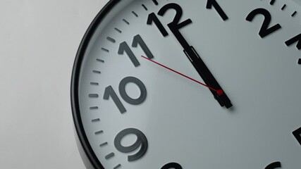 Round clock shows one minute to twelve, close-up. Classic clock time and New Year or New Day
