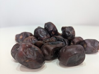 Close-up of a pile of dates on a white table, highlighting their glossy texture and rich caramel color. This composition underscores their role as a natural energy booster