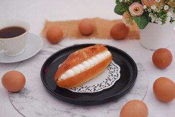 Eclair on a black plate with marble table