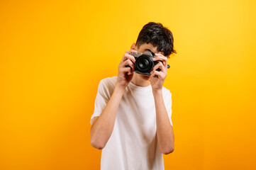 Teenager with camera, yellow background.