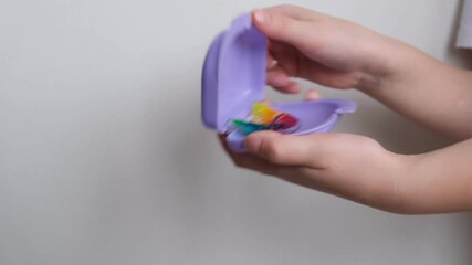 A dental plate for children of rainbow color. The child holds orthodontic braces in his hands to align the teeth and expand the jaw.	