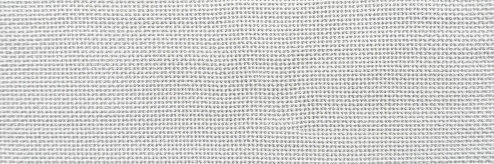 Close-up of a rough and textured canvas surface in neutral tones, threadbare