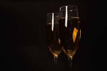 Two glasses of champagne glasses on luxury black background.