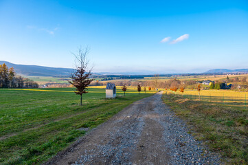 Fototapeta premium A peaceful autumn scene of the Stations of the Cross in the village of Sanov, with a sunny blue sky, rolling hills, and fields in the background, evoking a serene atmosphere