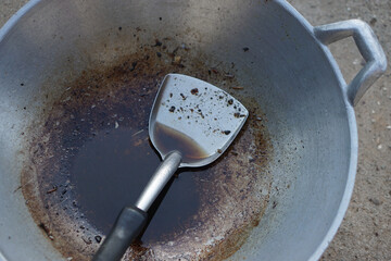 Close up cooked oil in a ladle with burnt stain of fried food scrape in pan. Concept, unhealthy...