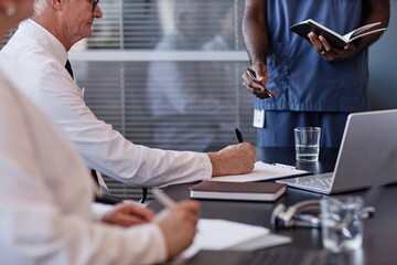 Side view of senior male head physician writing notes on paper planning patients treatment during...