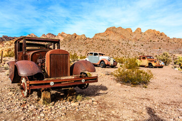 A rusted old car is parked in the desert