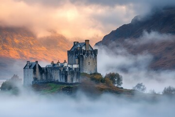 Naklejka premium A scenic image of a stone castle enveloped by mist and surrounded by hills draped in autumnal colors, offering a sense of mystery and timelessness to viewers.