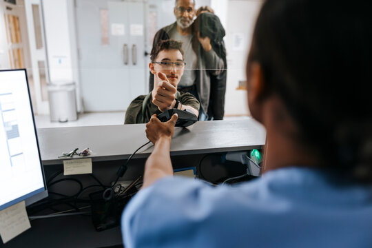 Teenage boy doing payment through smart watch at reception desk in medical clinic - Powered by Adobe