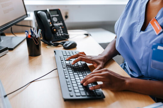 Female doctor typing on computer keyboard at medical clinic