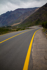 A winding road with yellow lines stretching into the distance, disappearing between towering mountain ranges on either side. A breathtaking blend of rugged nature and serene isolation.