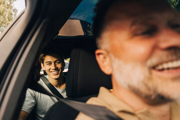 Portrait of smiling young man sitting in back seat of car