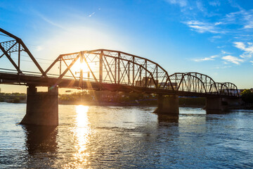 A bridge spans a river with a beautiful sunset in the background