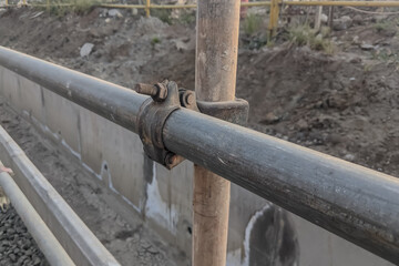 Metal scaffolding pipe clamp. Steel scaffolding and mounting parts for strength in construction sites or supports in view below. Close-up and select focus