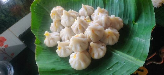 Maharashtrian sweet of Modak that is offered to Lord Ganesh, garnished with kesar (saffron) to be had with Ghee bowl and Lord Ganpati in the background.