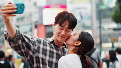 City, kiss and selfie with couple on street together in Japan for bonding, romance or tourism. Love, photograph and smile of Japanese woman with man in urban town for holiday, travel or vacation
