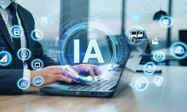 Hands of a businessman typing on a laptop and a hologram with the initials IA. Artificial intelligence concept