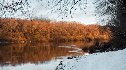 Serene riverside scene with vibrant sunset colors and the quiet beauty of winter