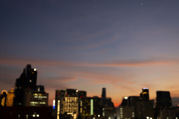 Blurred cityscape at twilight with bokeh lights and a softly colored evening sky.