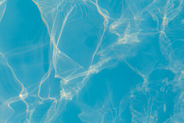 Close-up of vibrant blue swimming pool water with bright sunlight reflections creating dynamic, abstract patterns on the surface, evoking a sense of energy and freshness.
