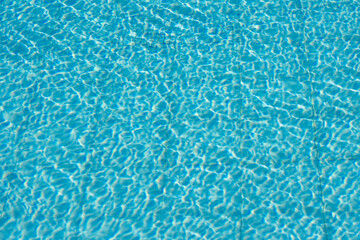 Blue water surface with intricate light reflections and rippling patterns, exuding summer vibes..