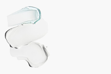Smears of white cosmetic cream and blue transparent gel on a light background